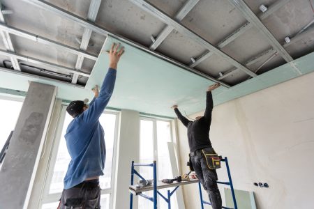 Workers fitting panel into frame of ceiling. High quality photo